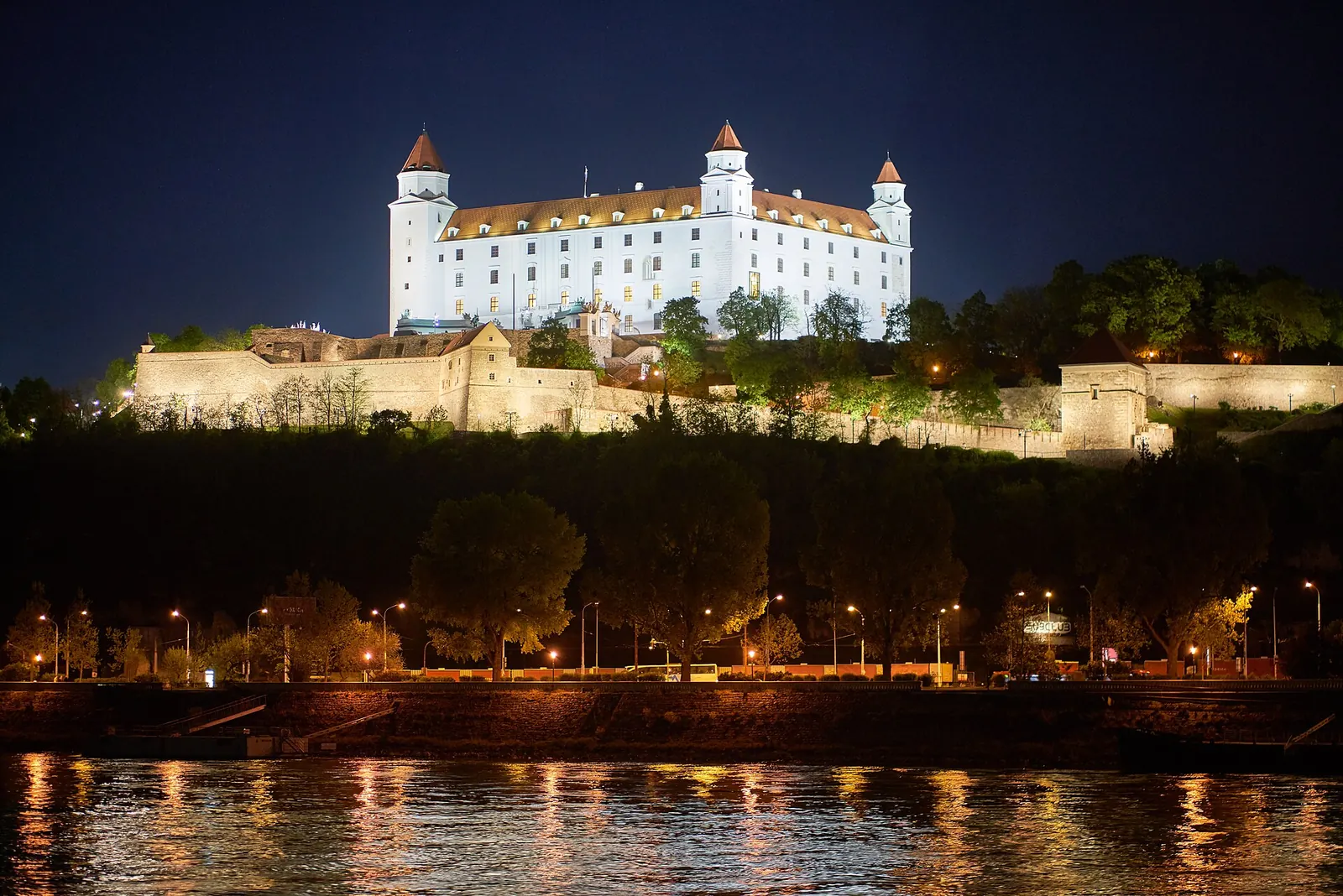 Bratislava Castle lit up at night above the Danube