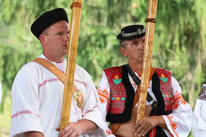 Two men in folk dress playing the fujara