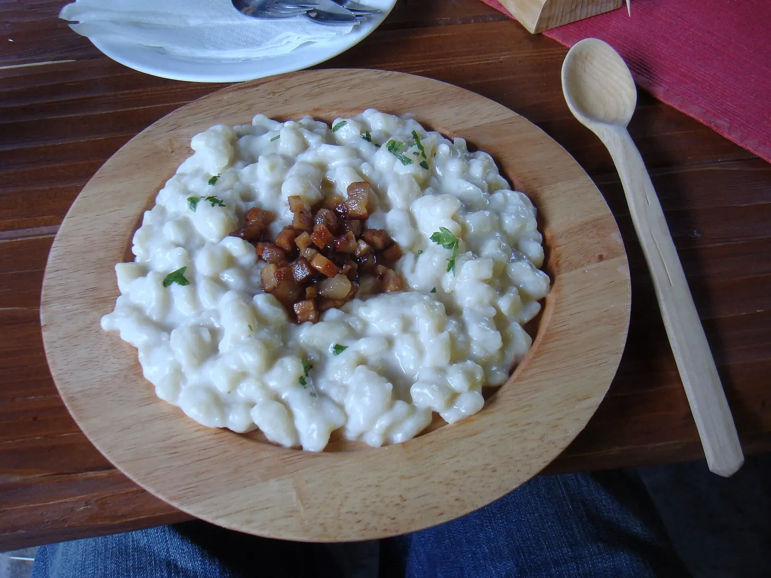 Bryndzové halušky with bacon on a wooden plate
